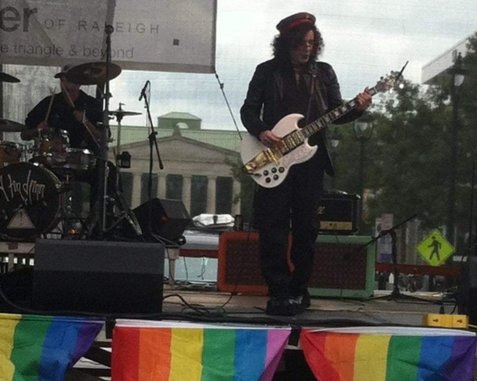 Eliot Wilcox playing guitar and an LGBTQ+ event