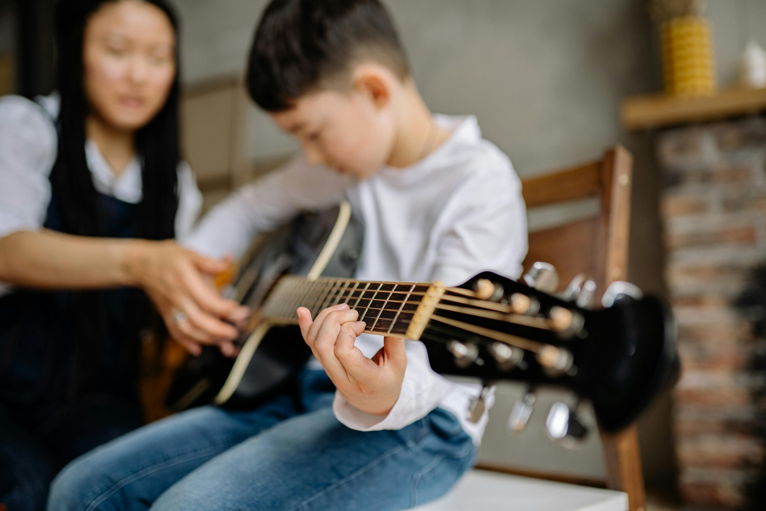 Teacher helping student learn how to play the electric guitar